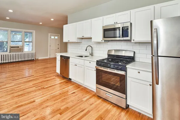 a kitchen with stainless steel appliances white cabinets a stove a sink and a microwave