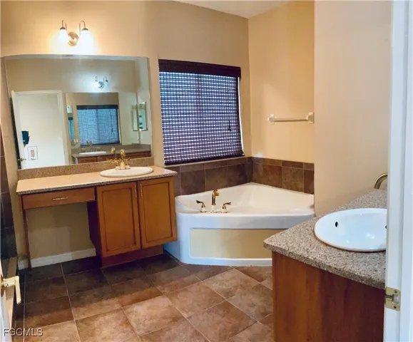 a bathroom with a tub a sink and a large mirror
