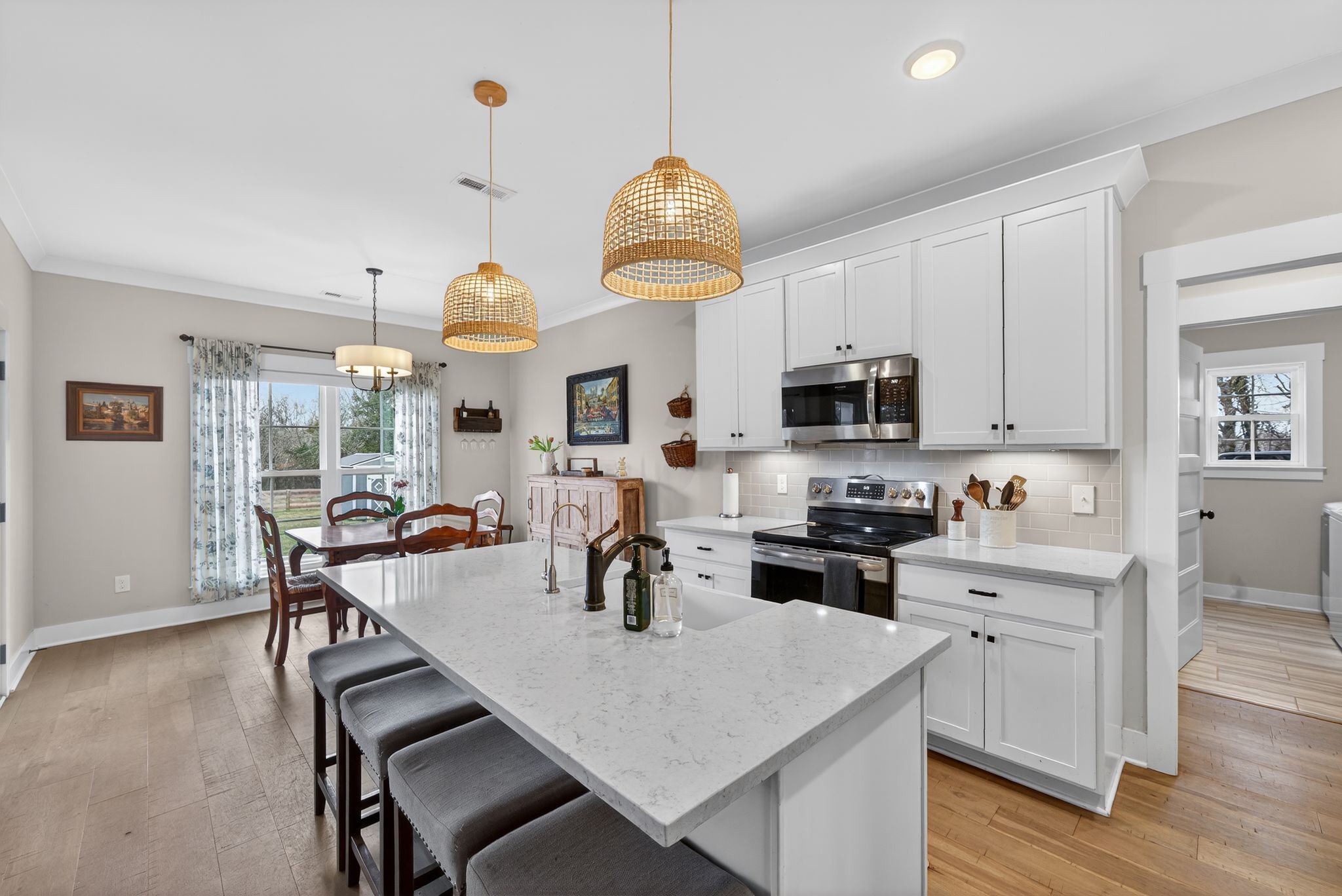 3834 Holly Grove Road Lascassas, TN 37085 - Photo 11 of 60 a kitchen with a stove a sink dishwasher a dining table and chairs with wooden floor