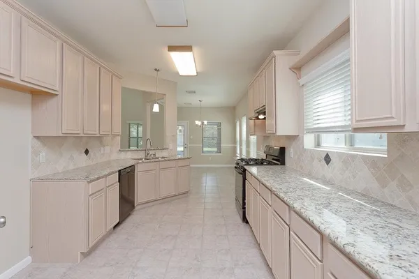 a large kitchen with granite countertop a sink and white cabinets