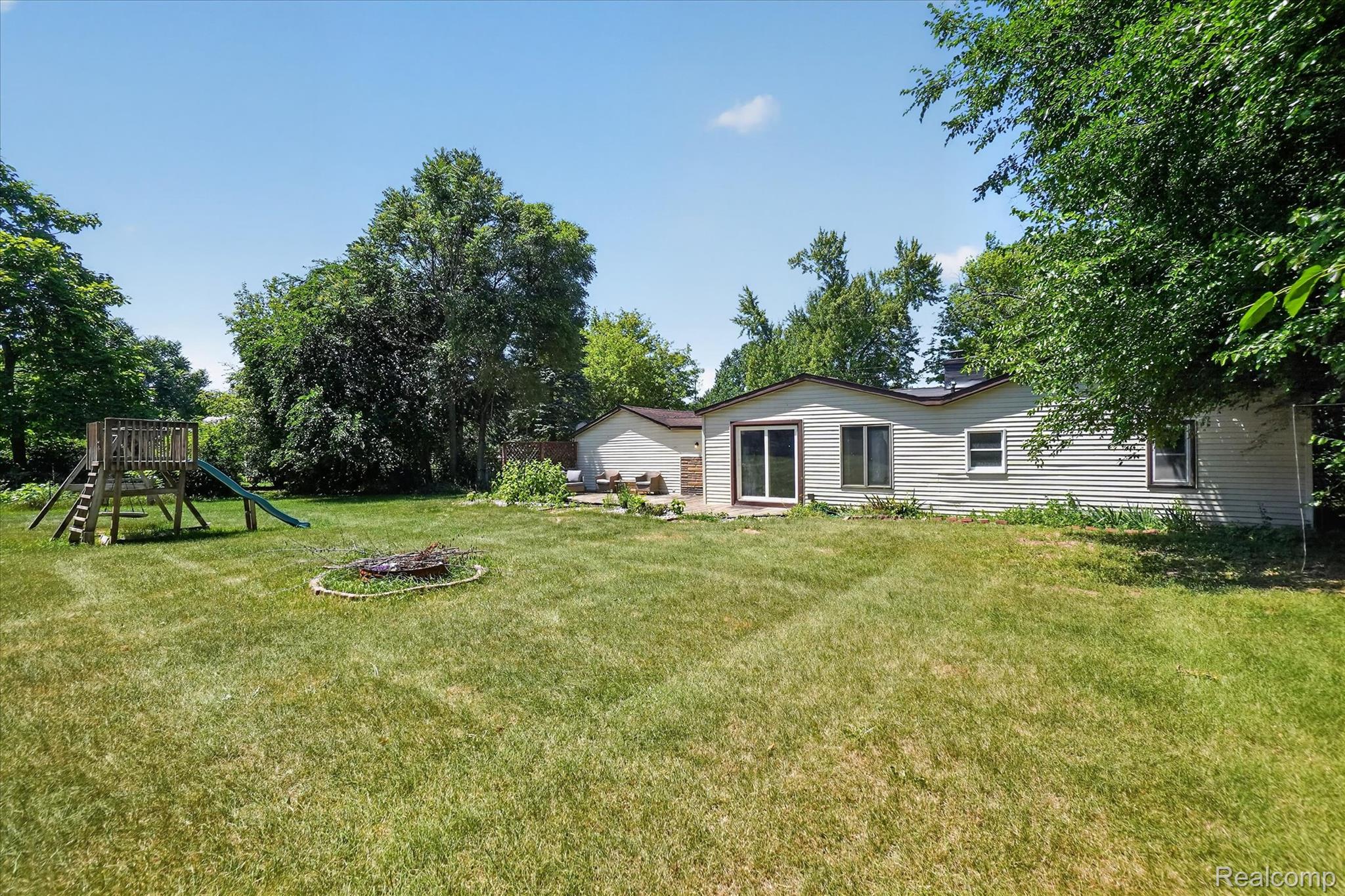 508 Deland Road Flushing, MI 48433 - Photo 31 of 38 Expansive backyard featuring a large grassy area, mature trees, and a visible fire pit