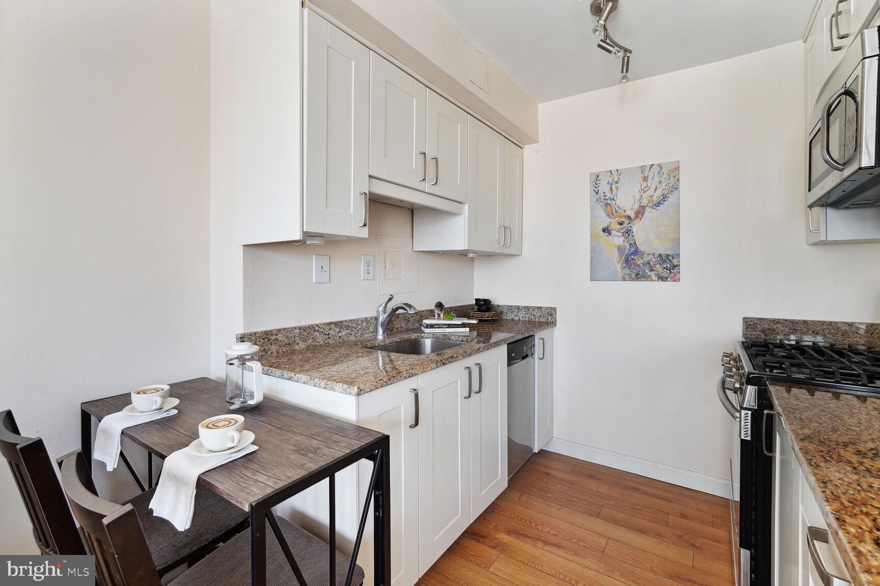 522 21st Street Northwest, Unit 903 Washington, DC 20037 - Photo 11 of 20 a kitchen with stainless steel appliances granite countertop a stove top oven a sink a dining table and chairs with wooden floor