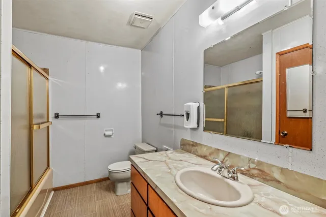 a bathroom with a granite countertop sink toilet and shower a mirror