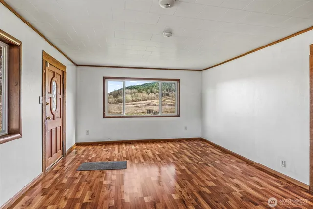 a view of an empty room with wooden floor and a window