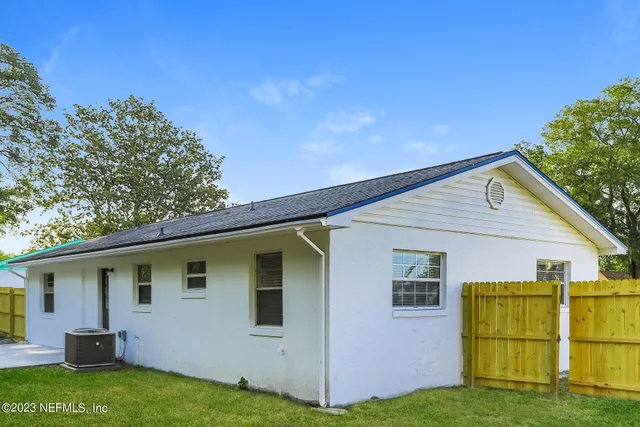 a view of backyard of house with wooden fence and large trees