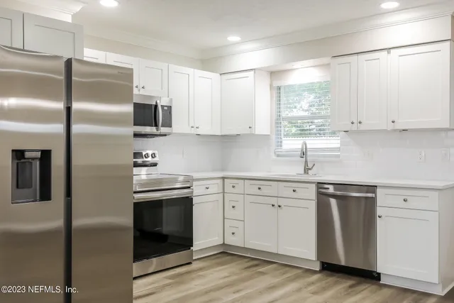 a kitchen with cabinets stainless steel appliances a sink and a window