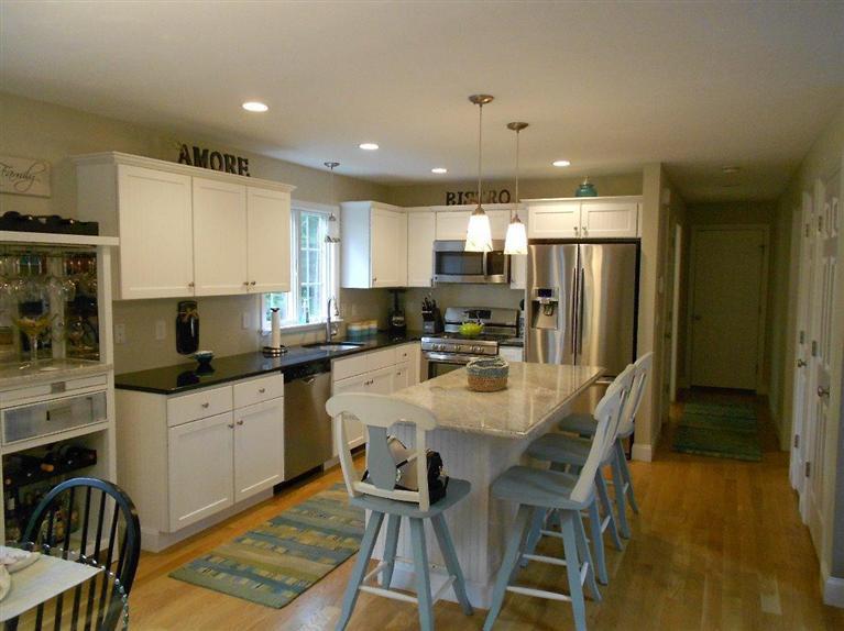 1171 Shootflying Hill Road Centerville, MA 02632 - Photo 4 of 16 a kitchen with stainless steel appliances kitchen island granite countertop a dining table chairs refrigerator and sink
