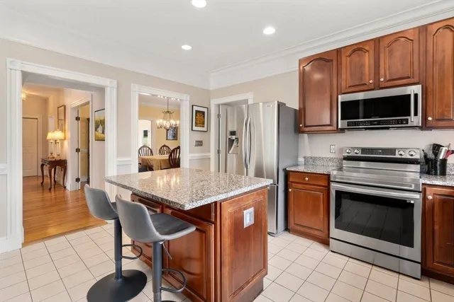 a kitchen with stainless steel appliances granite countertop a stove top oven a sink dishwasher a dining table and chairs with wooden floor