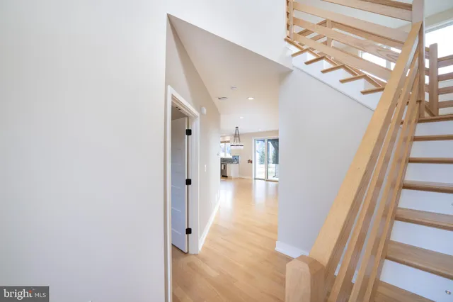 a view of an empty room with wooden floor and a ceiling fan
