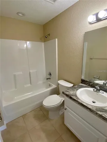 a bathroom with a granite countertop sink a toilet a mirror and a bathtub