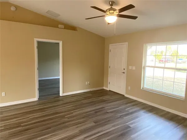a view of an empty room with wooden floor and a window