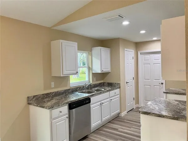 a kitchen with granite countertop a sink stove and cabinets
