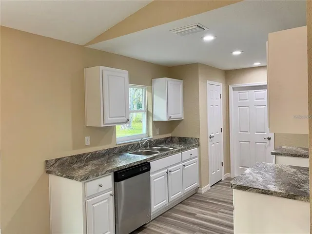 a kitchen with granite countertop a sink stove and cabinets