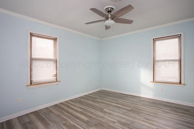 a view of empty room with wooden floor and fan