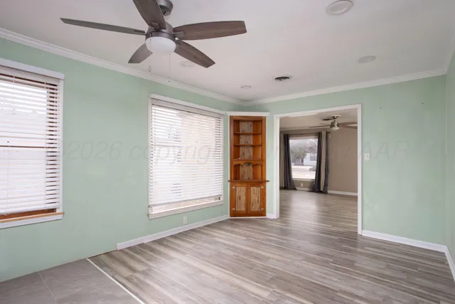 a view of an empty room with a window and wooden floor