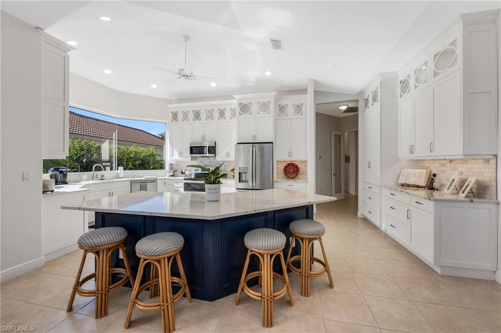 20001 Chapel Trace Estero, FL 33928 - Photo 4 of 32 a kitchen with stainless steel appliances kitchen island granite countertop a dining table chairs and white cabinets