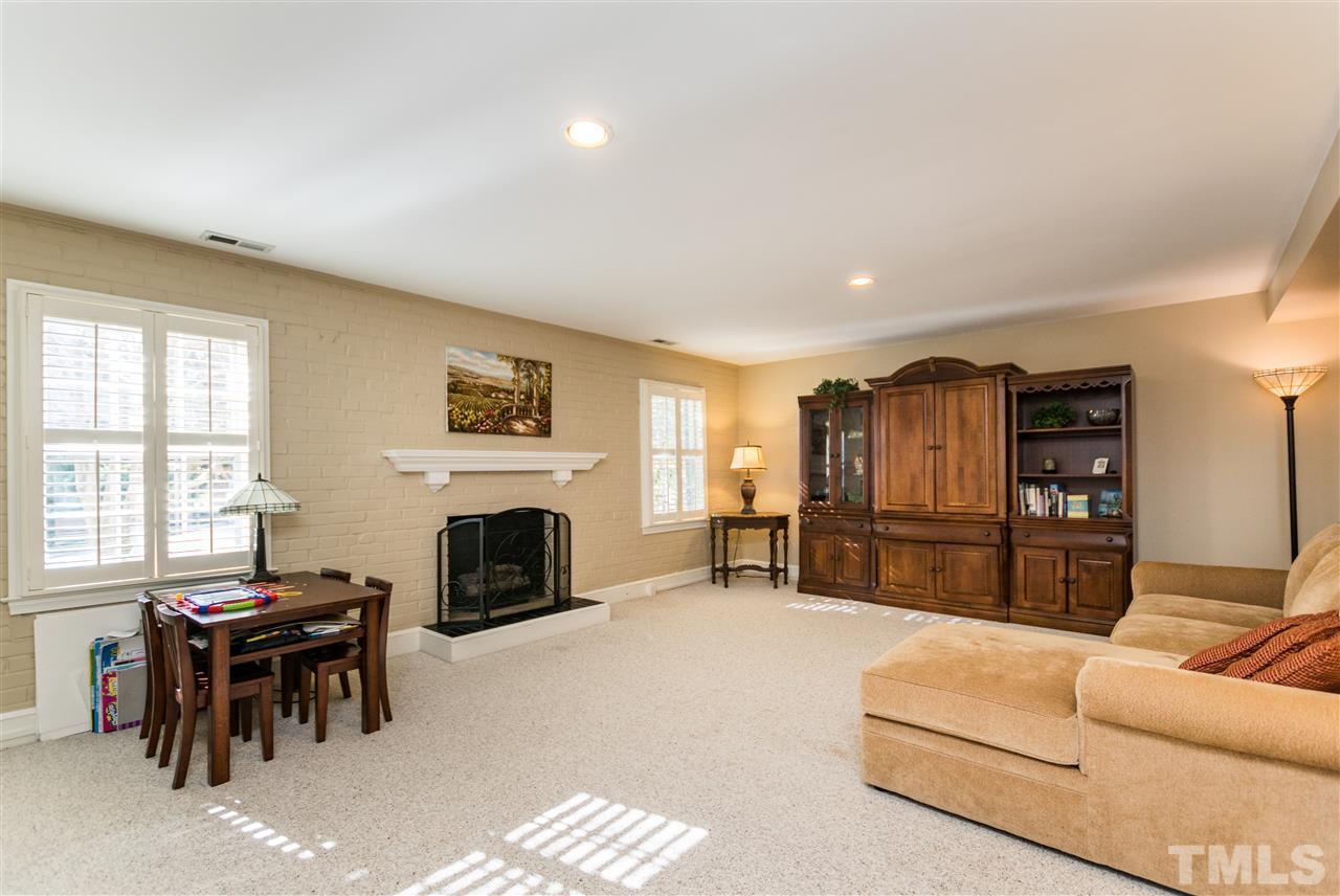 1422 Canterbury Road Raleigh, NC 27608 - Photo 22 of 25 a living room with furniture a fireplace and a flat screen tv