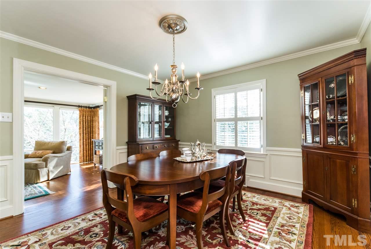 1422 Canterbury Road Raleigh, NC 27608 - Photo 5 of 25 a dining room with wooden floor a chandelier a wooden table and chairs