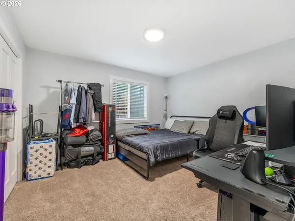 a bedroom with a bed and a computer on a desk next to a window