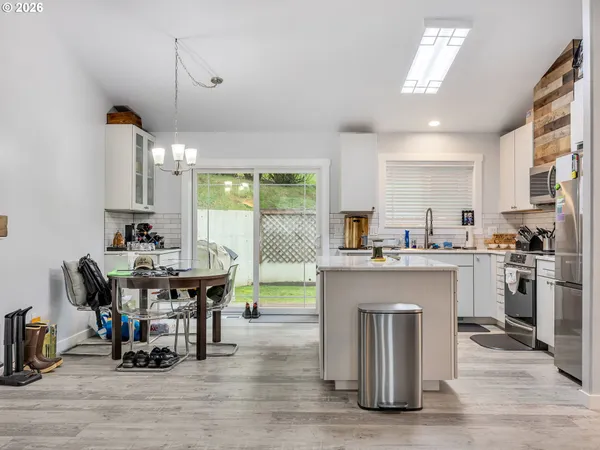 a kitchen with stainless steel appliances granite countertop a table chairs sink refrigerator and cabinets