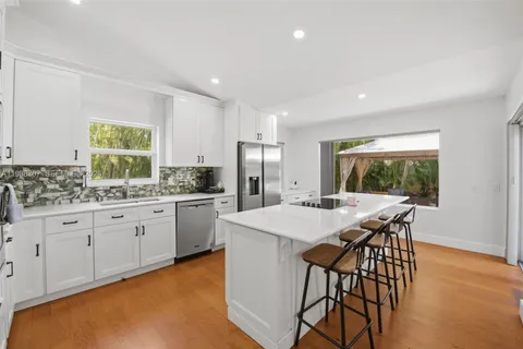 a kitchen with stainless steel appliances granite countertop table chairs sink and cabinets