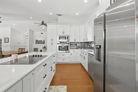 a large kitchen with kitchen island a counter top space a sink stainless steel appliances and cabinets