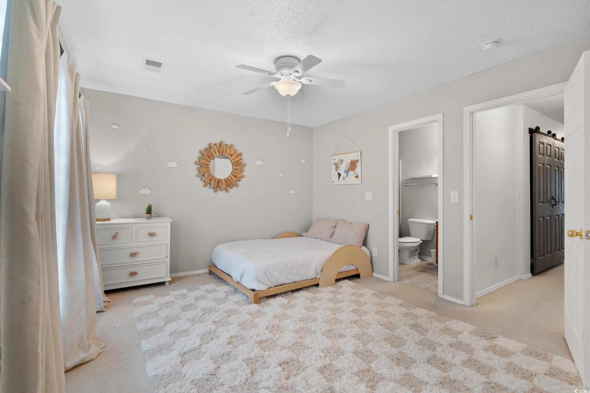 104 Olde Towne Way, Unit 5 Myrtle Beach, SC 29588 - Photo 14 of 24 Bedroom featuring light colored carpet, a ceiling fan, ensuite bath, and a textured ceiling