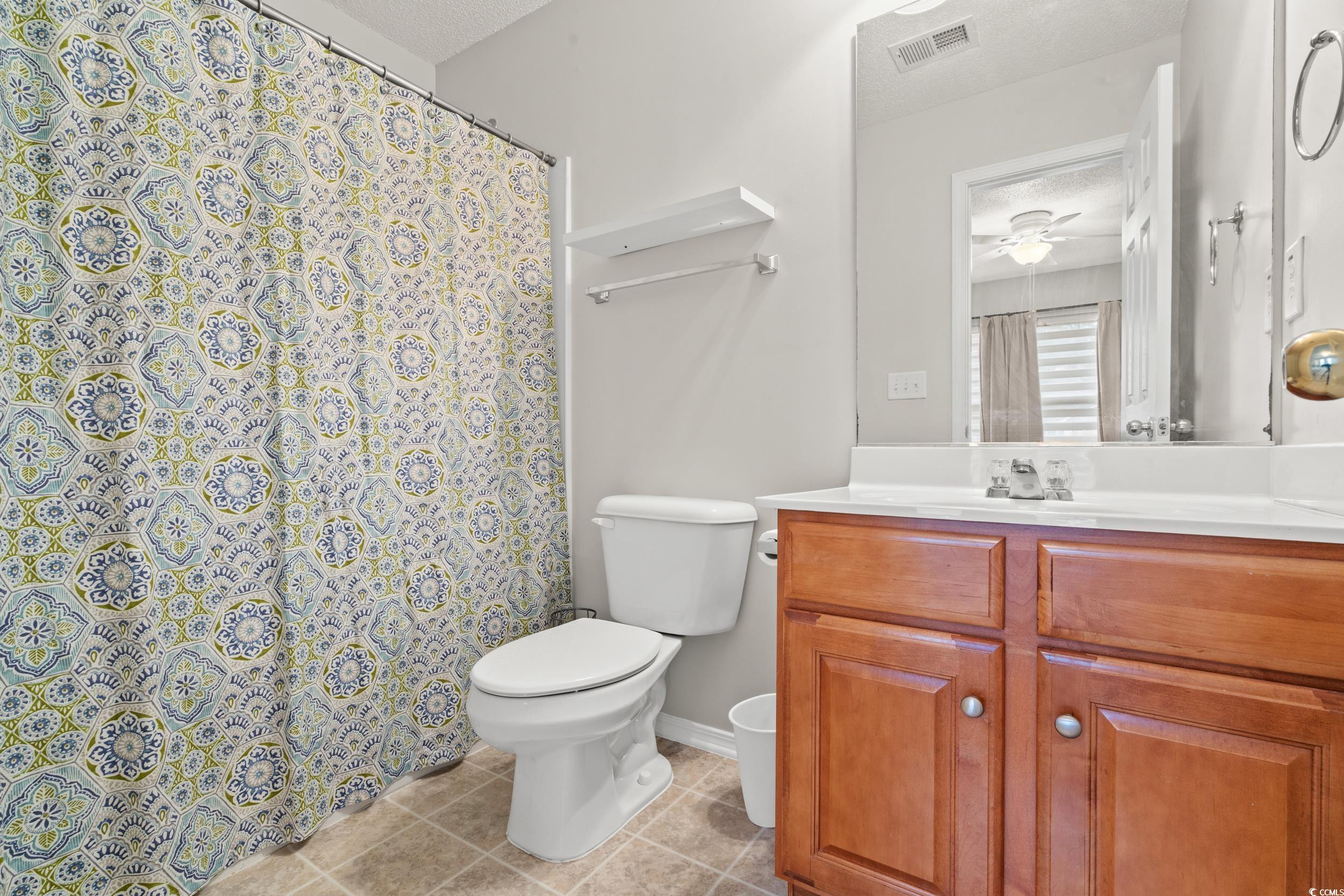 104 Olde Towne Way, Unit 5 Myrtle Beach, SC 29588 - Photo 15 of 24 Full bathroom featuring curtained shower, vanity, light tile patterned flooring, a ceiling fan, and a textured ceiling