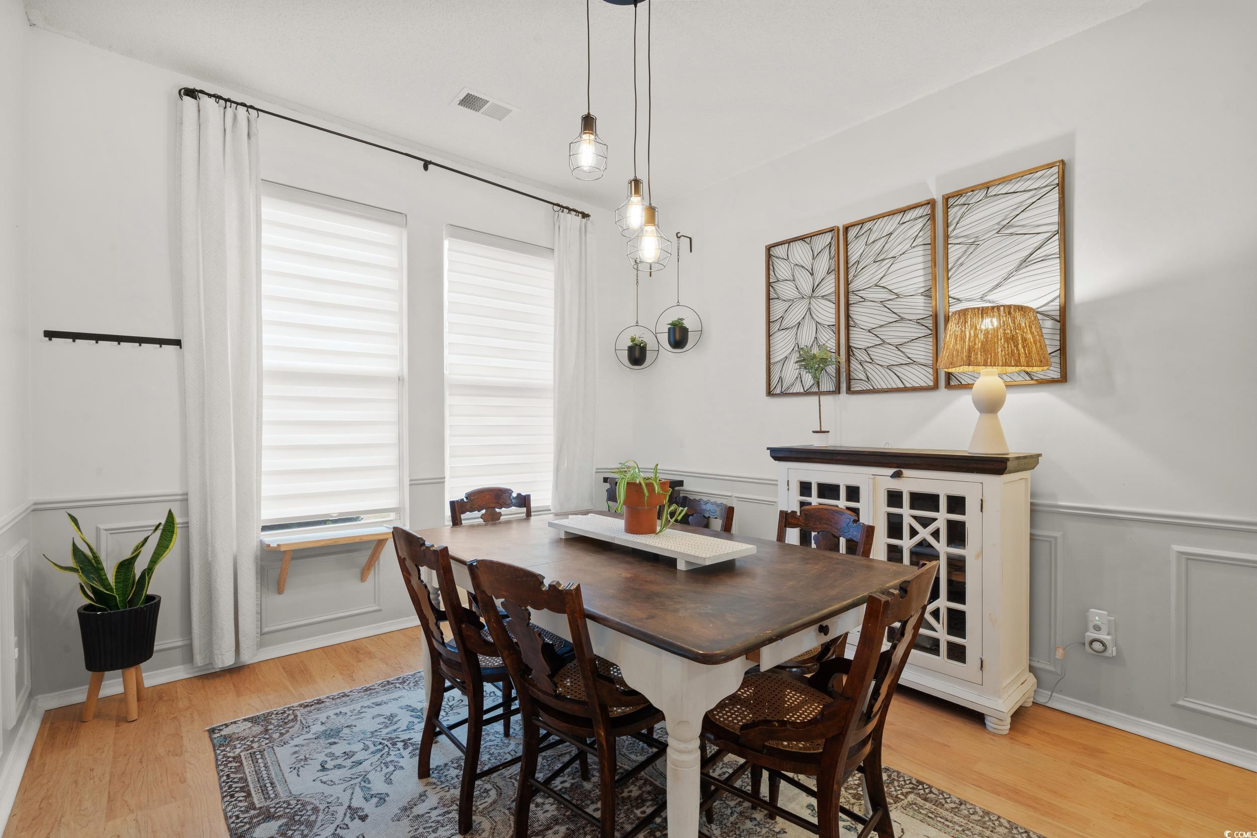 104 Olde Towne Way, Unit 5 Myrtle Beach, SC 29588 - Photo 4 of 24 Dining room featuring a decorative wall, a wainscoted wall, and light wood-style flooring