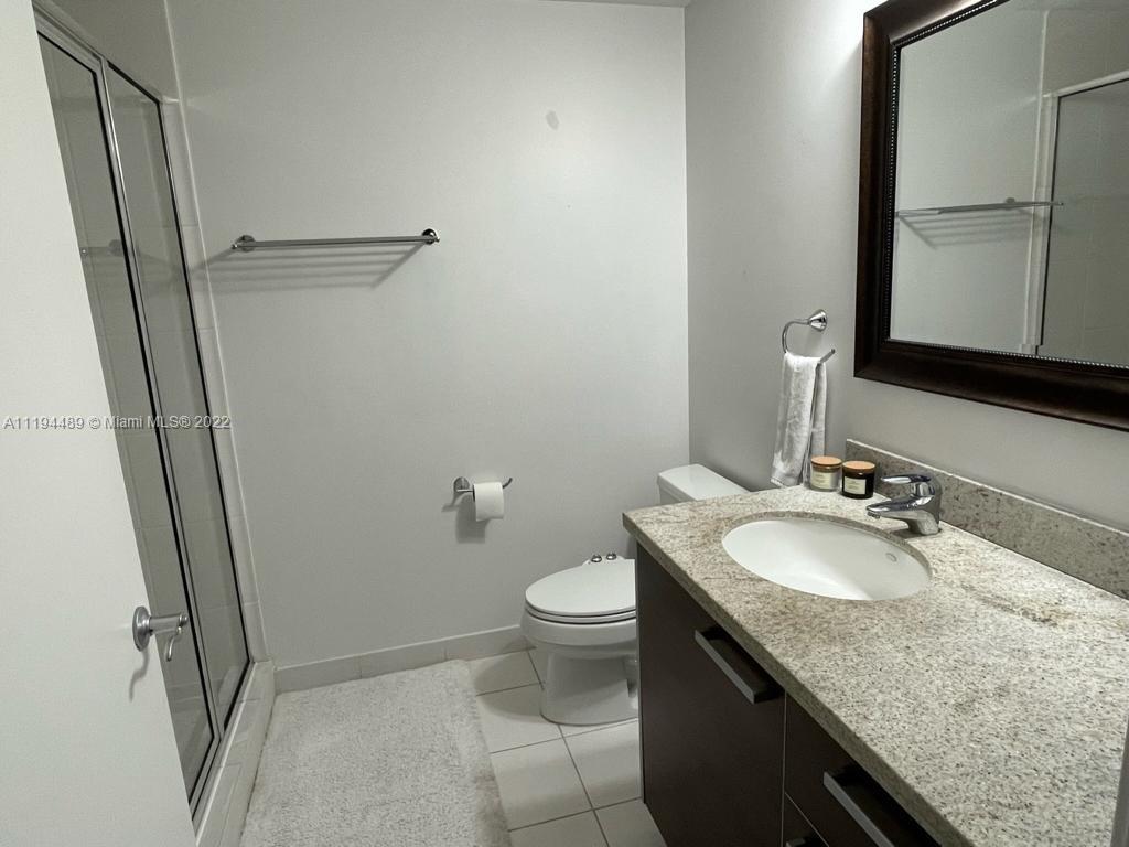 185 Southwest 7th Street, Unit 2703 Miami, FL 33130 - Photo 11 of 16 a bathroom with a granite countertop sink toilet and mirror