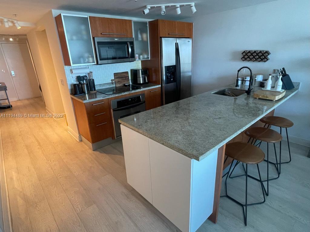 185 Southwest 7th Street, Unit 2703 Miami, FL 33130 - Photo 6 of 16 a kitchen with stainless steel appliances granite countertop a sink and a refrigerator
