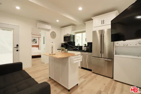 a kitchen with stainless steel appliances granite countertop a refrigerator a stove a microwave oven a sink dishwasher and white cabinets with wooden floor