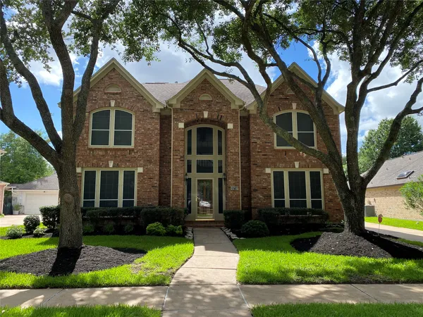 a front view of a house with a garden and trees