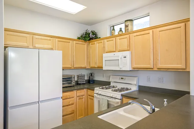 a kitchen with stainless steel appliances granite countertop a refrigerator sink and white cabinets