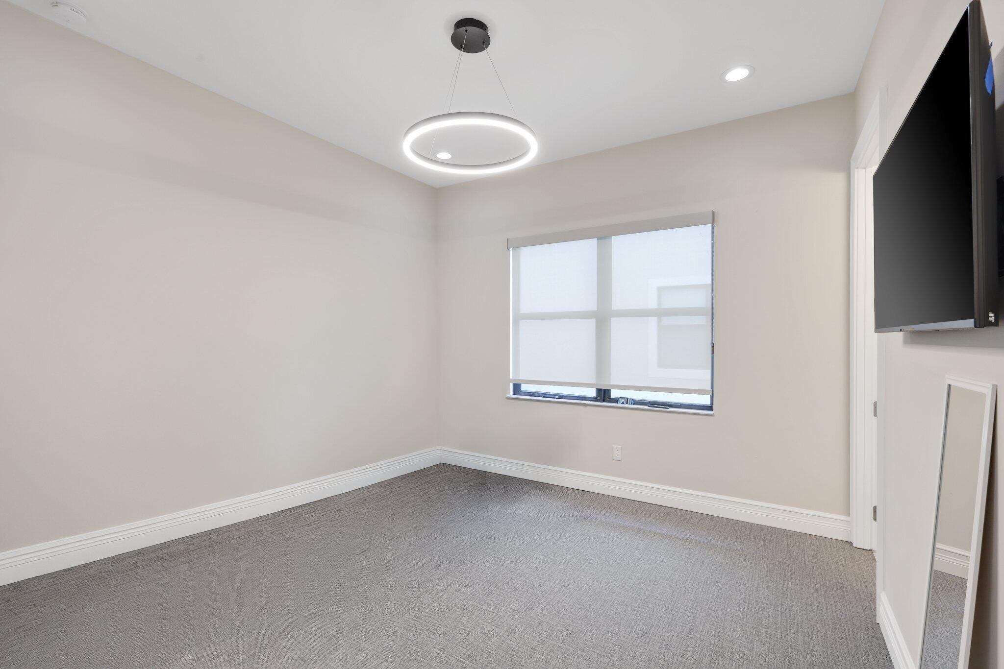 17432 Ponte Chiasso Drive Boca Raton, FL 33496 - Photo 74 of 117 an empty room with a flat screen tv and windows