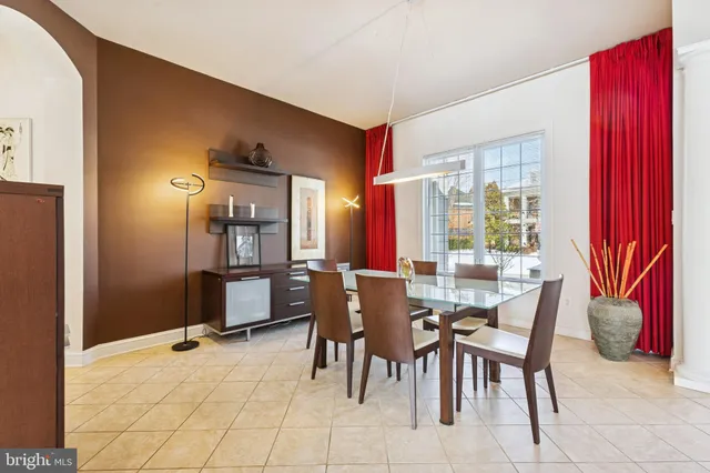 a dining room with furniture a fireplace a rug a potted plant and a large window