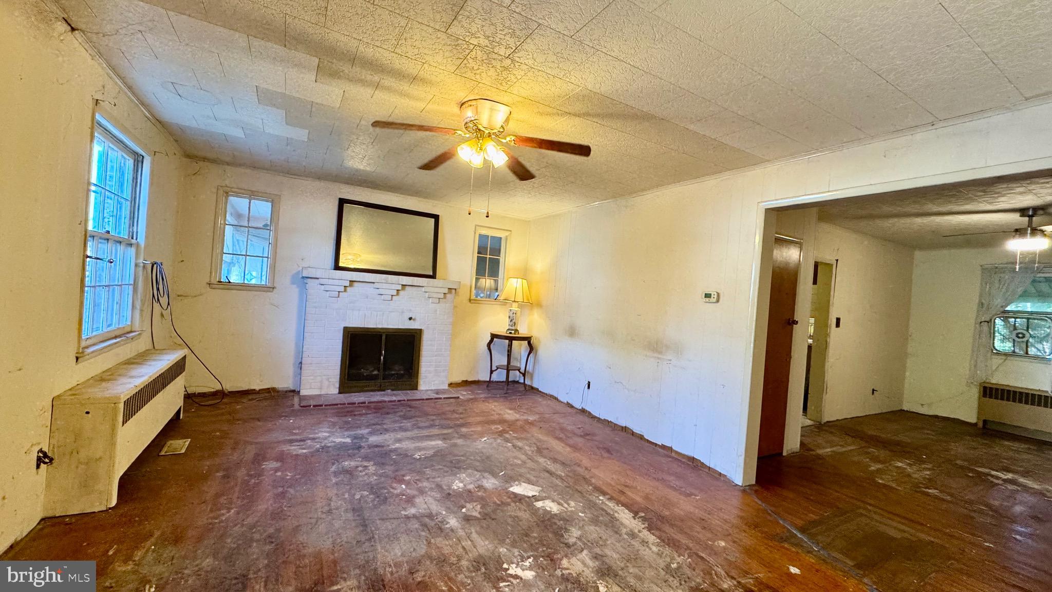 1 Potomac Street Crisfield, MD 21817 - Photo 3 of 15 a view of a livingroom with a fireplace a chandelier fan and windows
