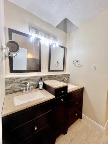 a bathroom with double vanity and a mirror