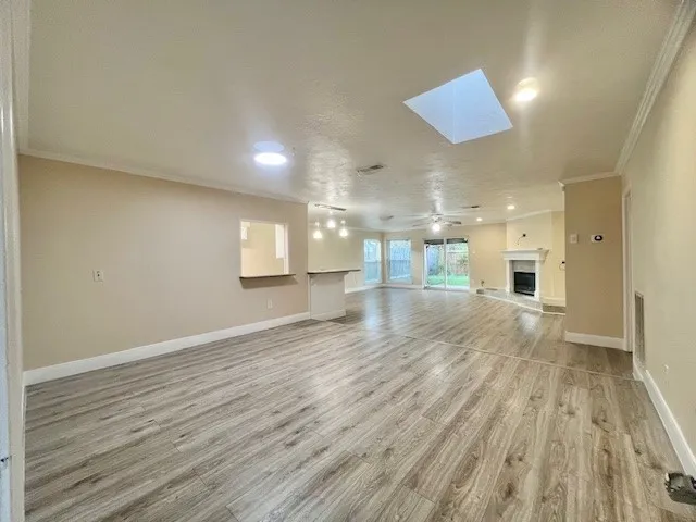 an empty room with wooden floor and a kitchen