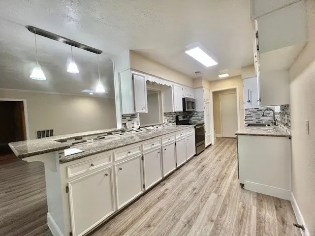 a large kitchen with cabinets wooden floor and stainless steel appliances
