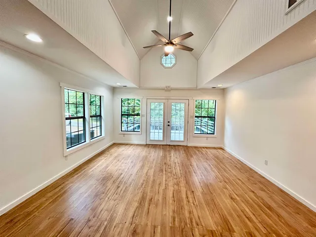 a view of an empty room with wooden floor and a window