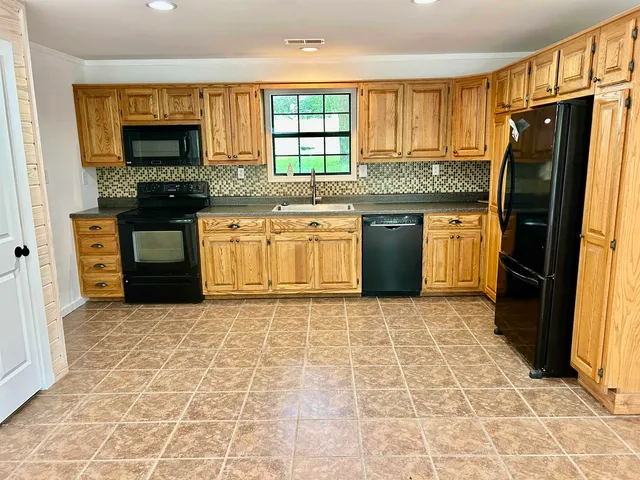 a kitchen with granite countertop a stove a refrigerator and a stove top oven