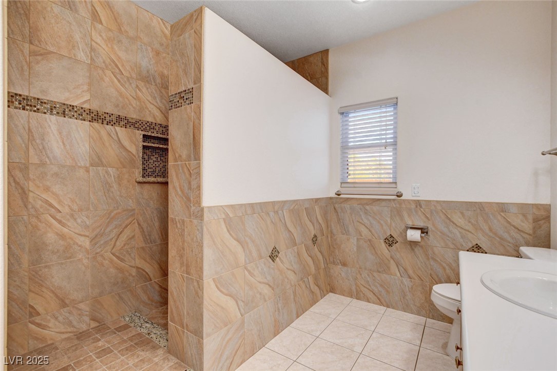 1104 Endora Way Boulder City, NV 89005 - Photo 13 of 36 Bathroom with tile walls, a tile shower, vanity, tile patterned flooring, and a wainscoted wall