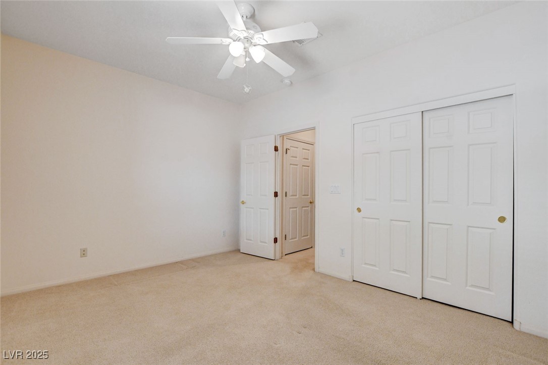 1104 Endora Way Boulder City, NV 89005 - Photo 17 of 36 Unfurnished bedroom with light carpet, ceiling fan, and a closet