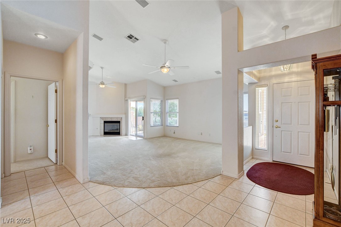 1104 Endora Way Boulder City, NV 89005 - Photo 5 of 36 Foyer entrance with light tile patterned floors, light colored carpet, healthy amount of natural light, and a fireplace