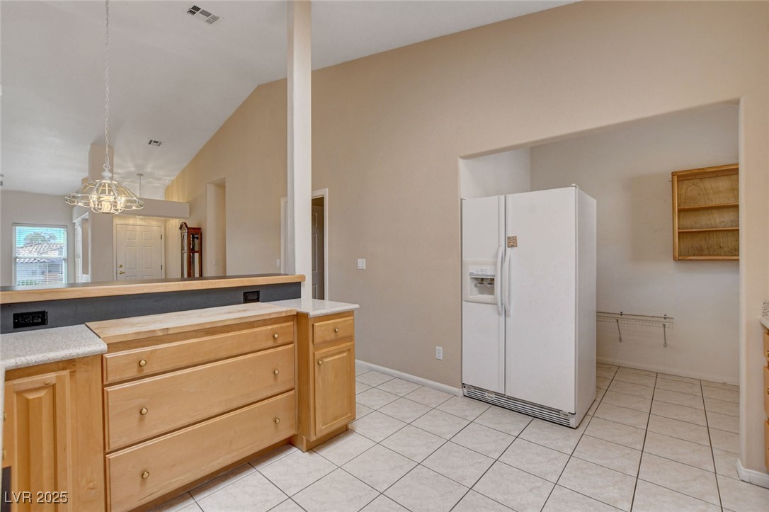 1104 Endora Way Boulder City, NV 89005 - Photo 6 of 36 Kitchen with white refrigerator with ice dispenser, wooden counters, light brown cabinets, light tile patterned floors, and decorative light fixtures