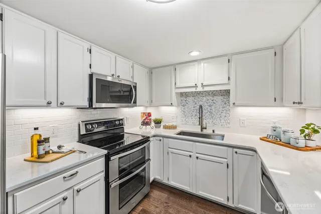 a kitchen with stainless steel appliances white cabinets sink and stove