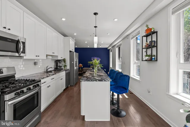 a kitchen with stainless steel appliances kitchen island granite countertop a stove a sink and a refrigerator