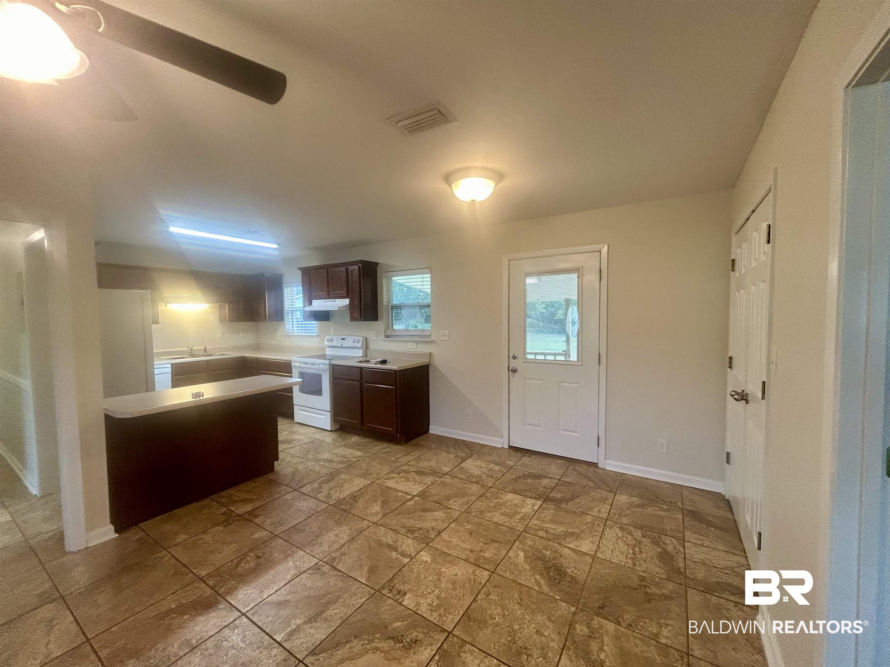 187 Van Hoosen Road Flomaton, AL 36441 - Photo 11 of 29 Kitchen with dark brown cabinetry, light countertops, white appliances, and healthy amount of natural light