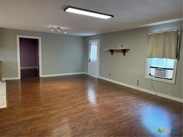 an empty room with wooden floor cabinet and windows